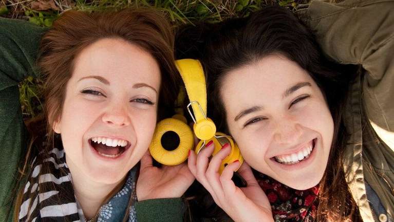 two teen girls sharing headphones